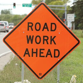 A highway work zone sign reads, 