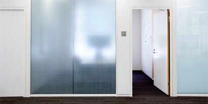 A private room with a door open and glass wall covered in 3M crystal privacy film designed to create privacy without blocking daylight.
