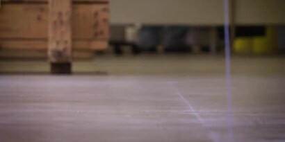 Video still of a rolling cart in the background of a cleaned floor ready for the application of floor marking tape
