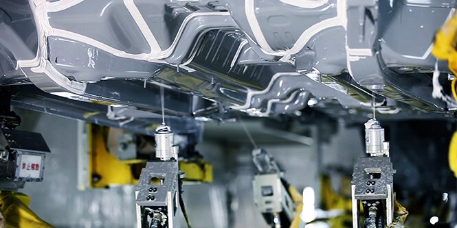 Seam sealants being applied to underbody coatings of a vehicle.
