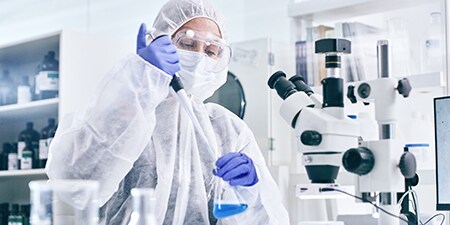 Female scientist pippetting liquid to a flask in lab
