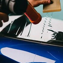 person pouring a glue onto a car window
