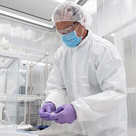 Man in lab attire holding 3M™ Dyneon™ High Temperature Perfluoroelastomers.