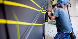 A man drawing lines using liquid paint on a bus 

