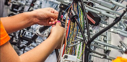 A worker uses protecting 3M wire harnesses to make complex electrical and electronic equipment.
