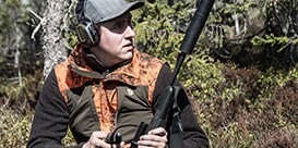 hunter wearing ear muffs listening for signals
