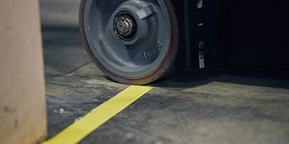 Closeup image of a vehicle wheel crossing a taped yellow lane marking
