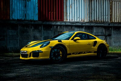 yellow sports car parked next to a wall

