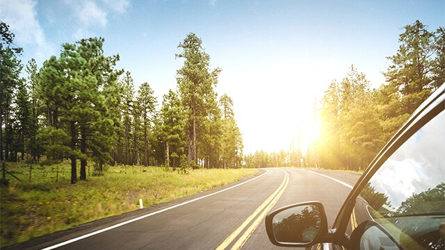 car driving down highway with sun shining ahead