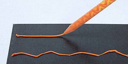 검은색 표면에 오랜지색 자동차 구조용 접착제 적용 시연의 와이드 샷
