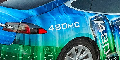 A close up of the back right side of a sedan wrapped in a blue and green 3m envision print wrap LX480mC & SV480mC film.
