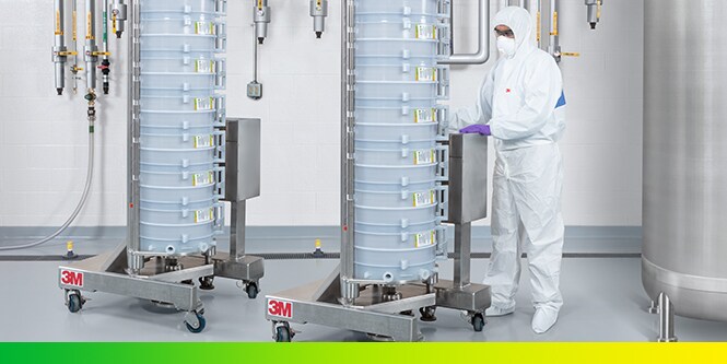 Engineer wearing mask and lab coat wheeling a 3M™ Encapsulated System Holder with 3M capsule products for bioprocessing

