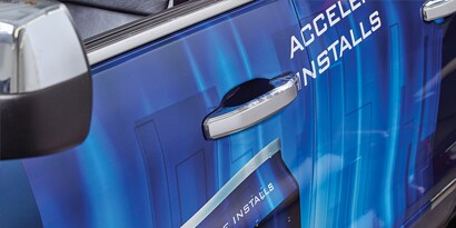 A close up of a blue car's driver side door and handle, wrapped in 3M IJ180mC-10 print wrap film.
