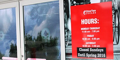 Exterior of a business with clear a clear glass automatic door and clear glass wall with an hours of operation sign on the glass door using 3M opaque film.
