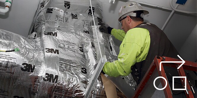 Image of a contractor installing a 3M fire barrier around ductwork
