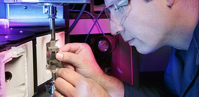  A man wearing safety glasses carefully examines an electrical connection.
