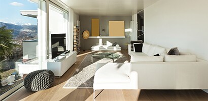 A residential living room with a large floor to ceiling window pane allowing sunlight in.

