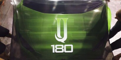 Two men applying a green 3M IJ180mC print wrap film over the hood of a sports car.
