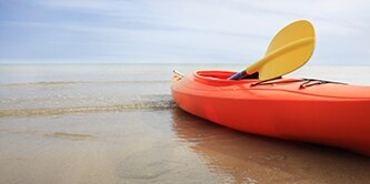 평화로운 해변 위의 주황색 카약 세트와 노란색 패들
