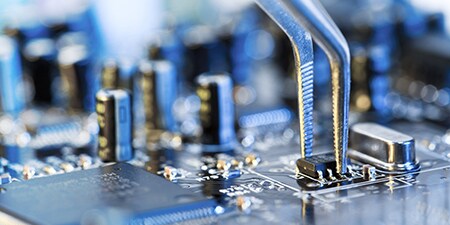 Pliers being used on a circuit board capacitor
