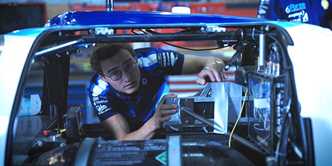 Man working on the inside of a racecar chassis
