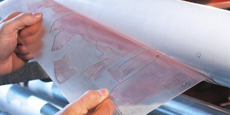 age of a worker pulling a printing plate off a sleeve
