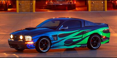 Black race car with green flames at night wrapped in 3M reflective film.
