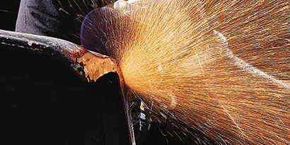 worker grinds metal with cubitron II fibre disc
