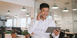 휴대폰과 태블릿을 들고 미소 짓고 있는 사람