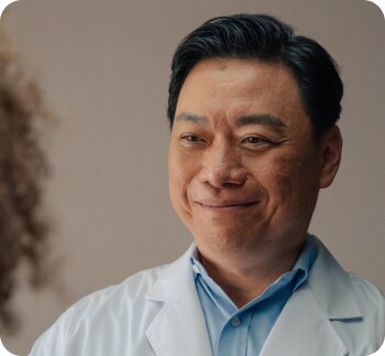 가운을 입고 미소 짓는 의사의 클로즈업
