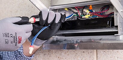 A man puts electrical wire in place with 3M Tape.
