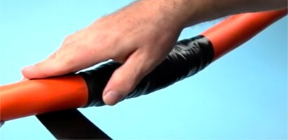 A man applies black 3M tape to repair an electrical cable jacket.
