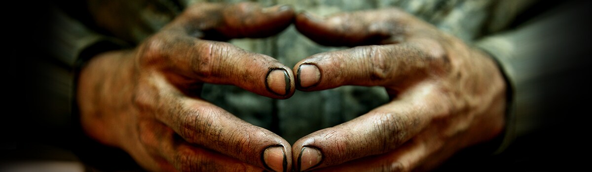 Closeup image of dirty hands with the fingertips pressed together
