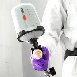 A person in a protective suit holding a spray object