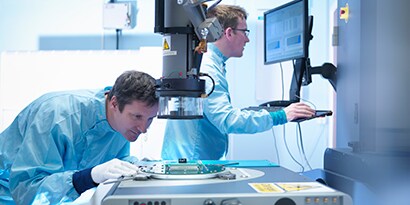 Image of electronics workers checking components in a lab.
