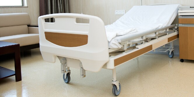 Image of an empty hospital bed in a room setting

