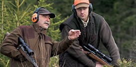 two men wearing ear muffs talking to eachother
