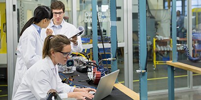 Image of engineers working on a laptop and assembling robotics in a lab.
